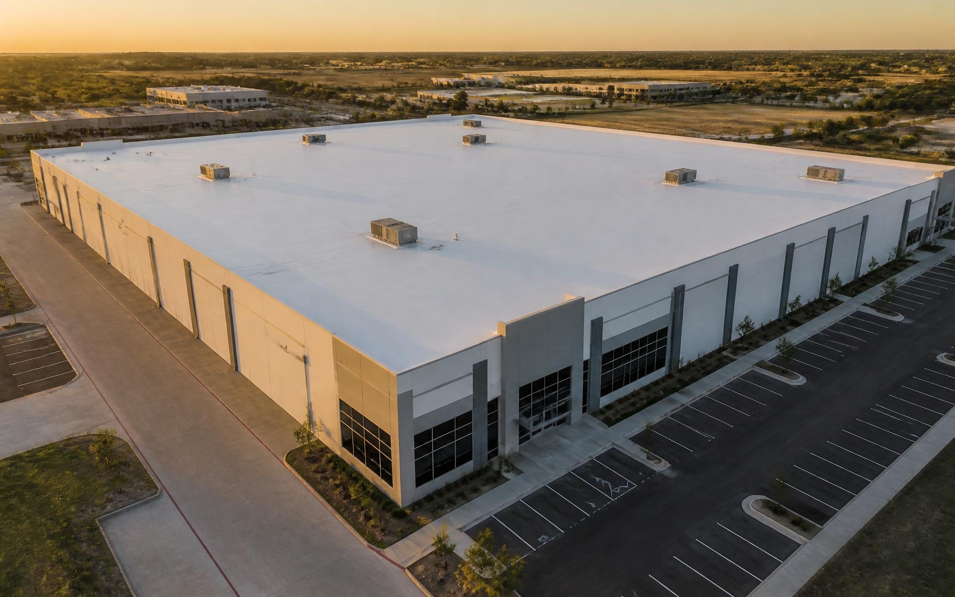 Aerial view of a commercial building with a white flat membrane roof at sunset